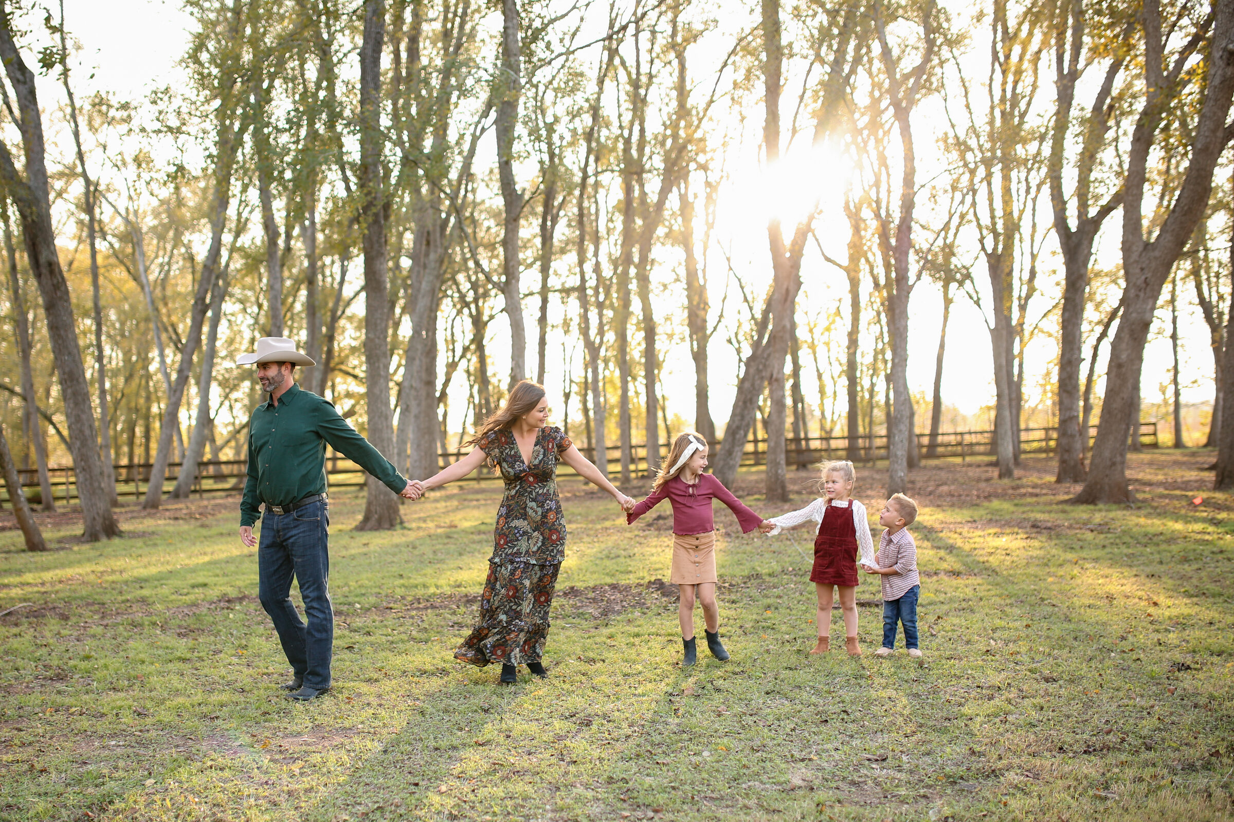 A family holding hands and walking together through golden, sunlit trees