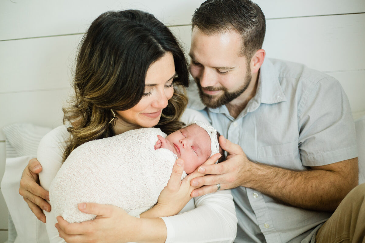 New parents nuzzling their baby girl in her pearl headband