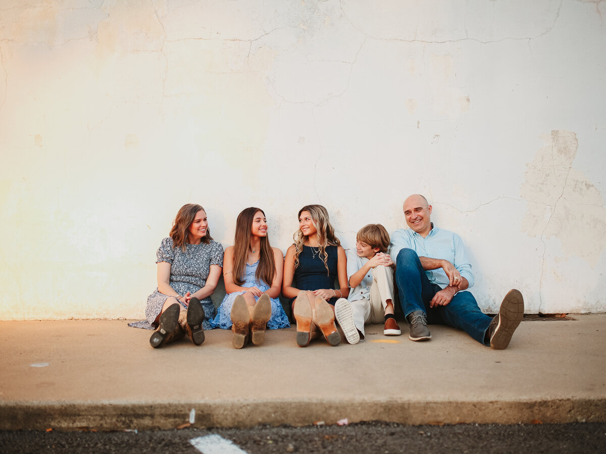 The Williams family sitting together against a sunlit white wall