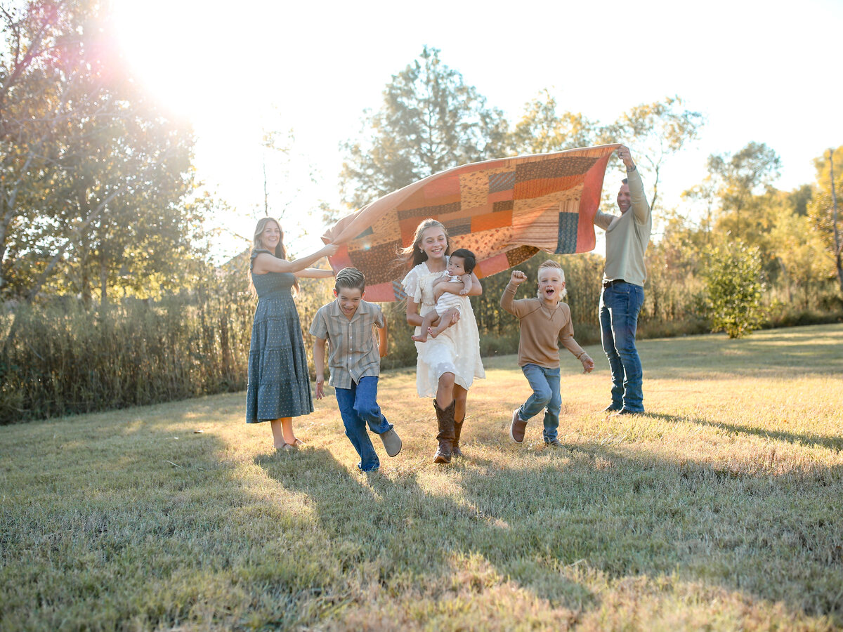The West family running under a quilt in golden evening light