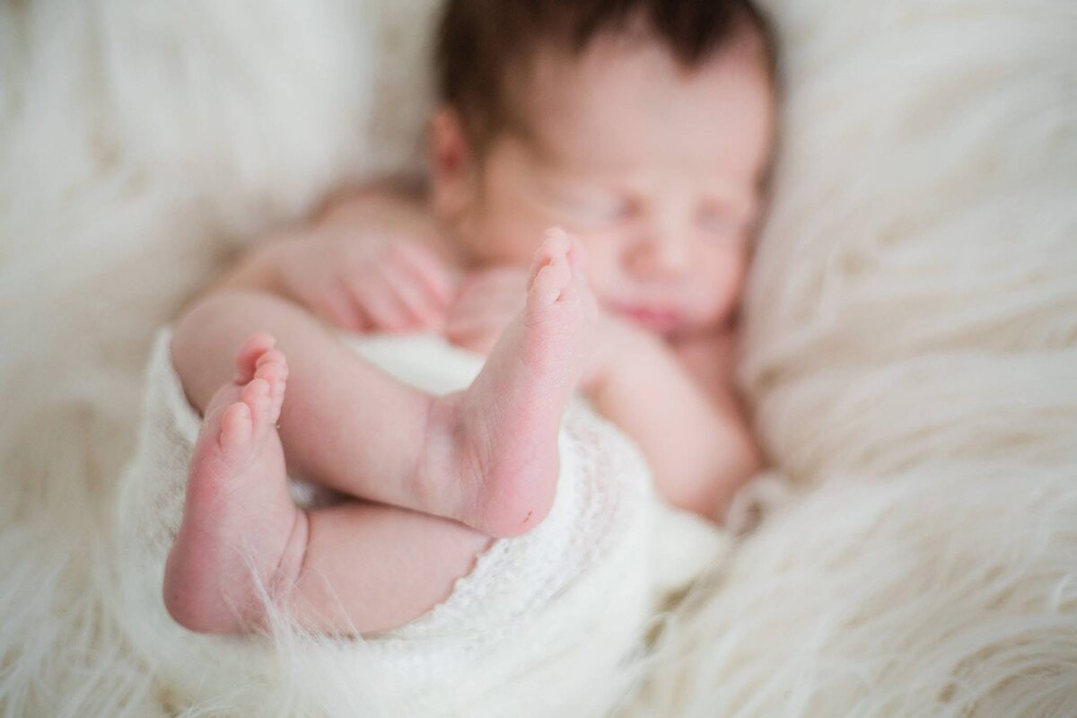 Tiny newborn toes crossed on a soft fur blanket