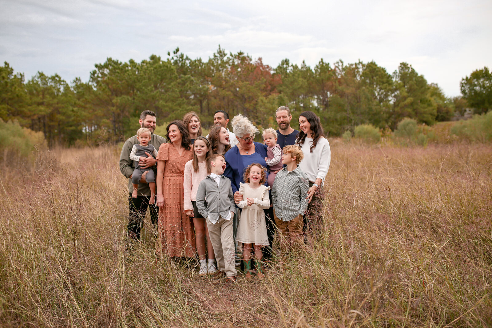 Grandma surrounded by the whole family in a field of pink autumn grass