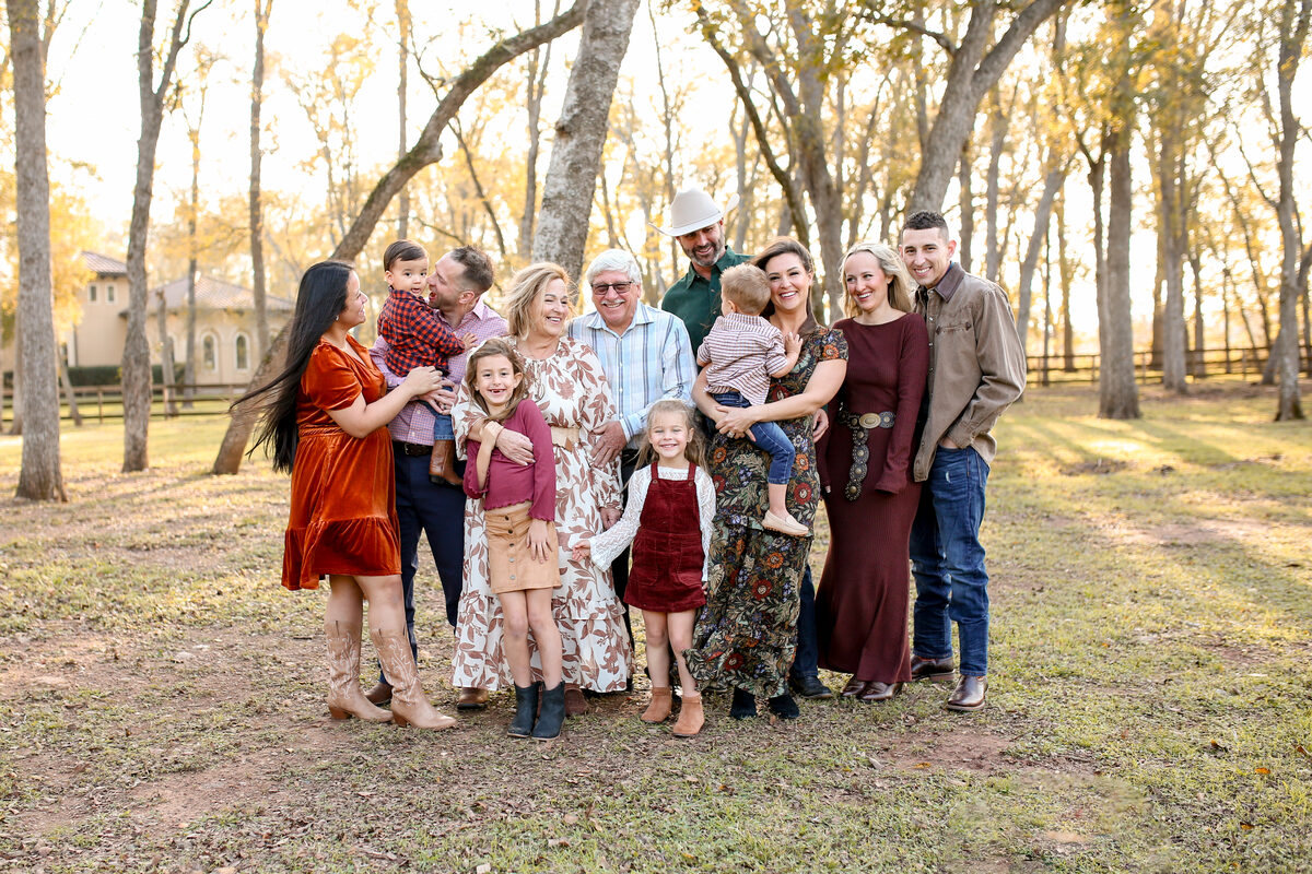 A large multigenerational family laughing together under golden autumn trees