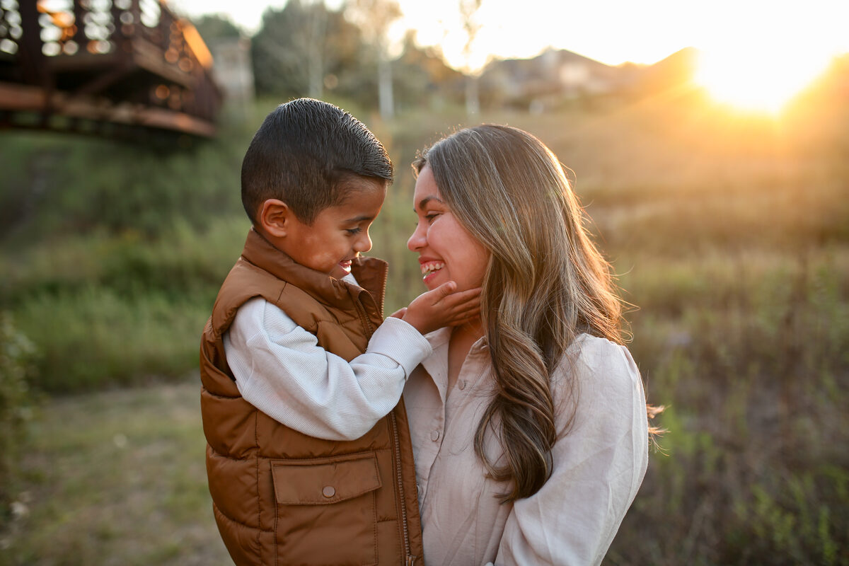 A mother holding her laughing son close at golden hour