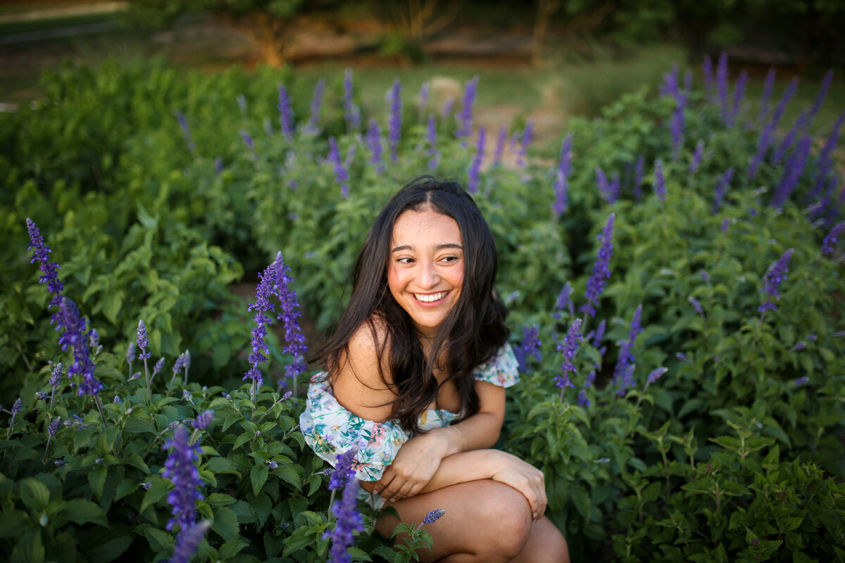 A high school senior laughing among purple salvia blooms