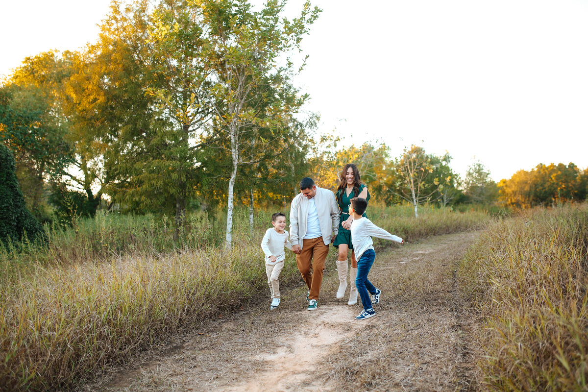 A family of four running hand in hand down a golden trail