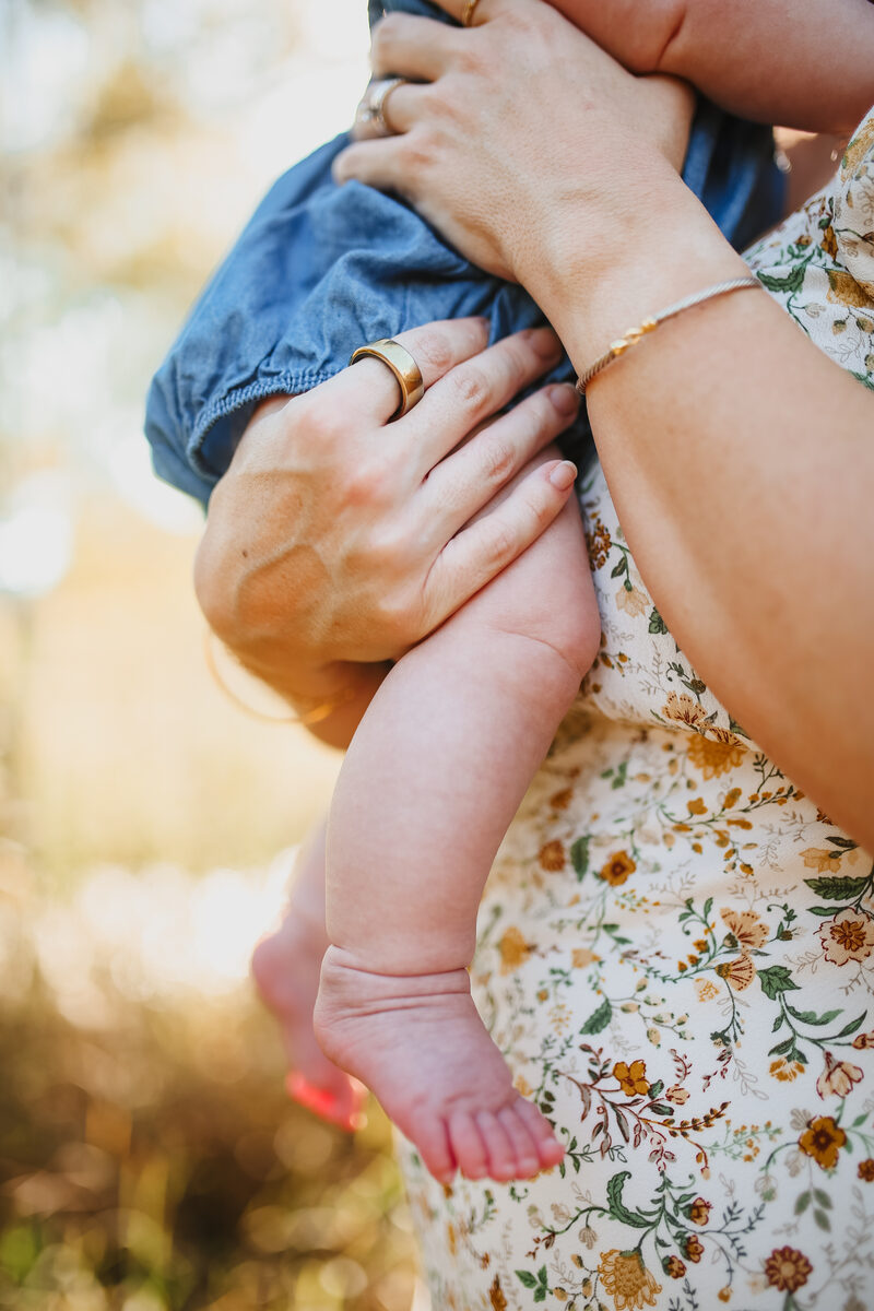 A mother's hands cradling her baby's tiny feet in golden light