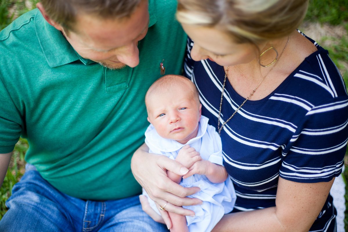 New parents cradling their newborn son on the grass