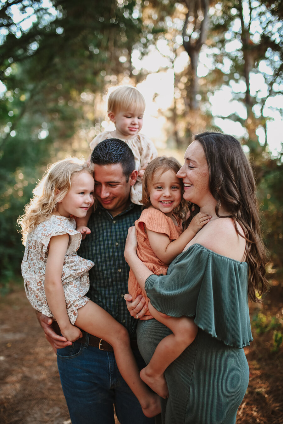 Family of five cuddled together in golden autumn woods